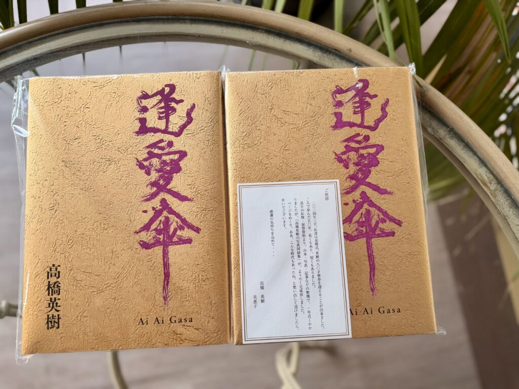 金色の表紙に紫の筆文字で「逢愛傘」と書かれた本が2冊。1冊にはご夫妻からのご挨拶状が添えられている