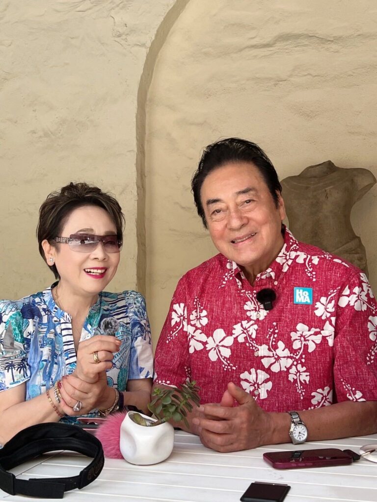 ホノルル美術館の中庭のテーブルで笑顔の高橋英樹さんと美惠子さん
