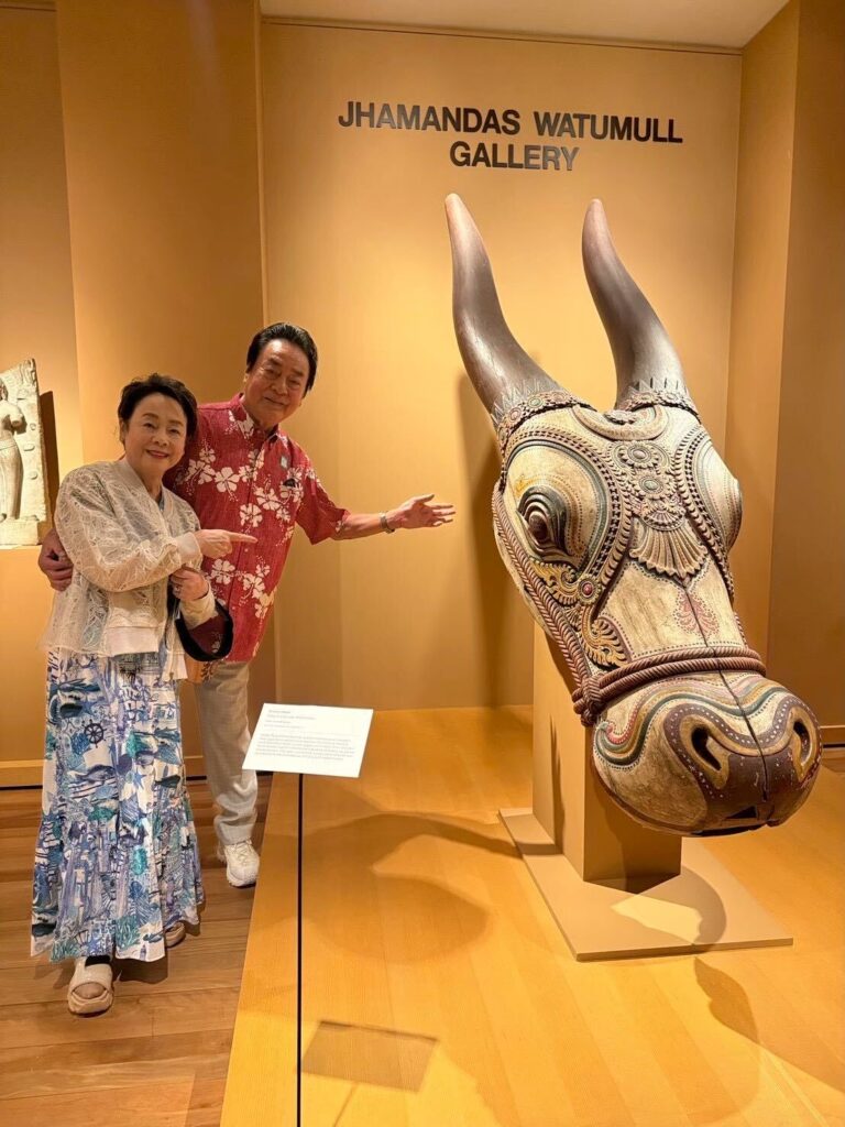 ホノルル美術館の展示室で彫刻を指し示す高橋英樹さんと美惠子さん